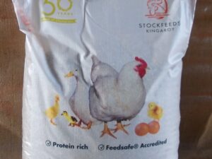 The image shows a bag of Kewpie Stockfeeds. The bag is labeled "Pullet Grower Mash + M/plt" and weighs 20 kg. It features illustrations of chickens and chicks, and includes text indicating it is "Protein rich" and "Feedsafe® Accredited." The bag also mentions "50 years" and has a logo with a rooster
