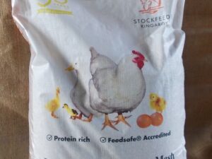 he image shows a bag of "Kewpie Premium Poultry Layer Mash." The bag is labeled as "Protein rich" and "Feedsafe® Accredited." It features images of chickens and chicks and indicates a weight of 20 kg net.