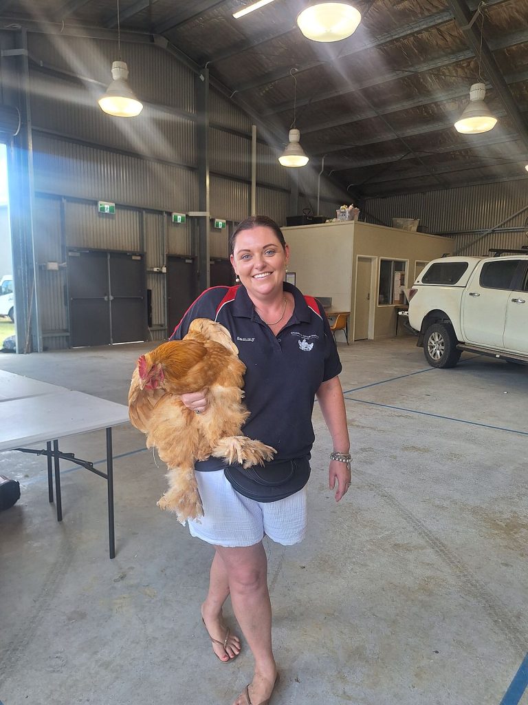 Sammy holding a buff Orpington hen in the Rosewood Showgrounds pavilion